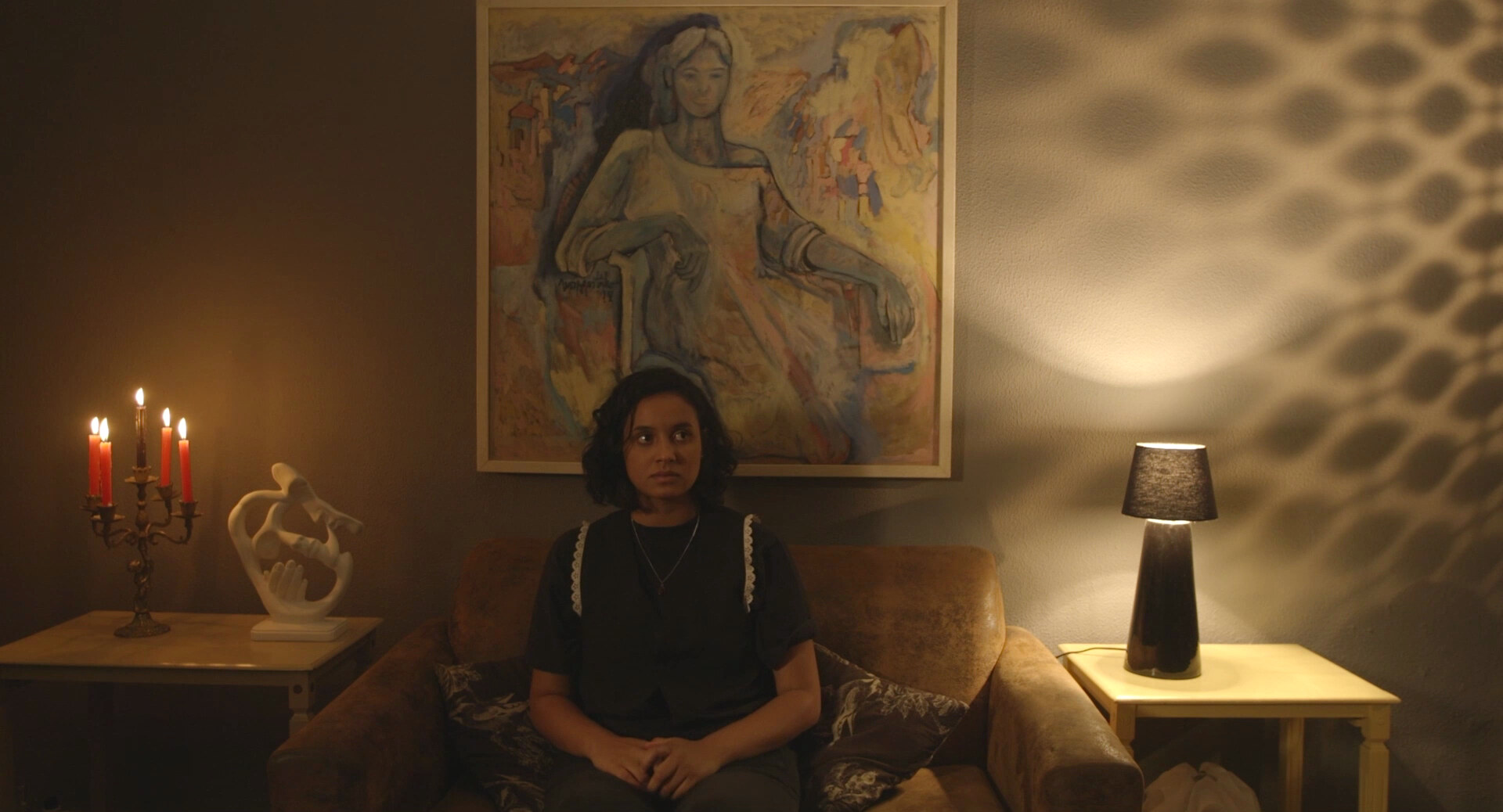 Mulher sentada em um sofá diante de um retrato